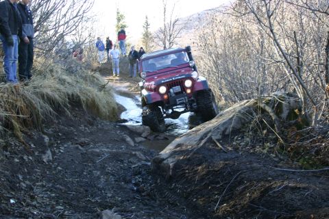 2003 Jeep TJ - A red Jeep Wrangler TJ navigates a challenging off-road course with onlookers present.