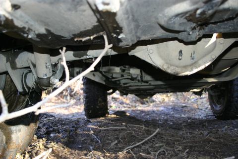 2003 Jeep TJ - Underside view of a vehicle's suspension and differential, resting on muddy terrain.
