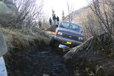 2003 Jeep TJ - A Ford F-Series truck maneuvers through a challenging off-road course with onlookers present.