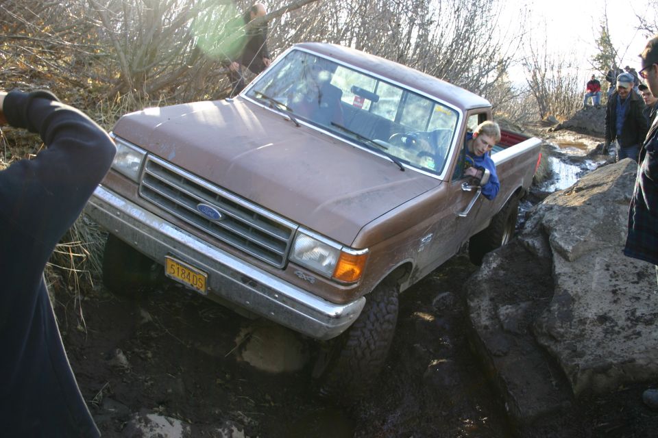 Brown 1987 Ford F-150 pickup truck navigating rocky terrain