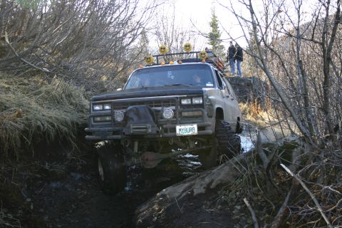 2003 Jeep TJ - Modified SUV tackling a challenging off-road trail with mud and rocks.