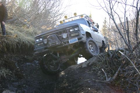 2003 Jeep TJ - This modified truck is tackling a challenging off-road course with steep inclines and rough terrain.