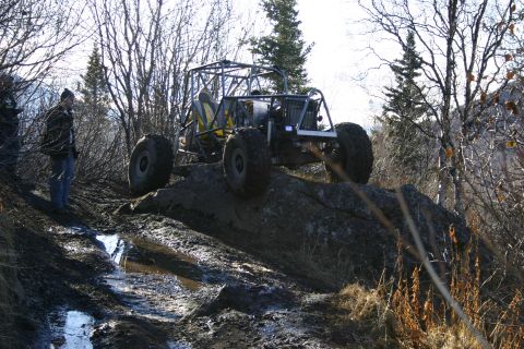 2003 Jeep TJ - A heavily modified off-road buggy navigates a challenging rocky and muddy terrain.