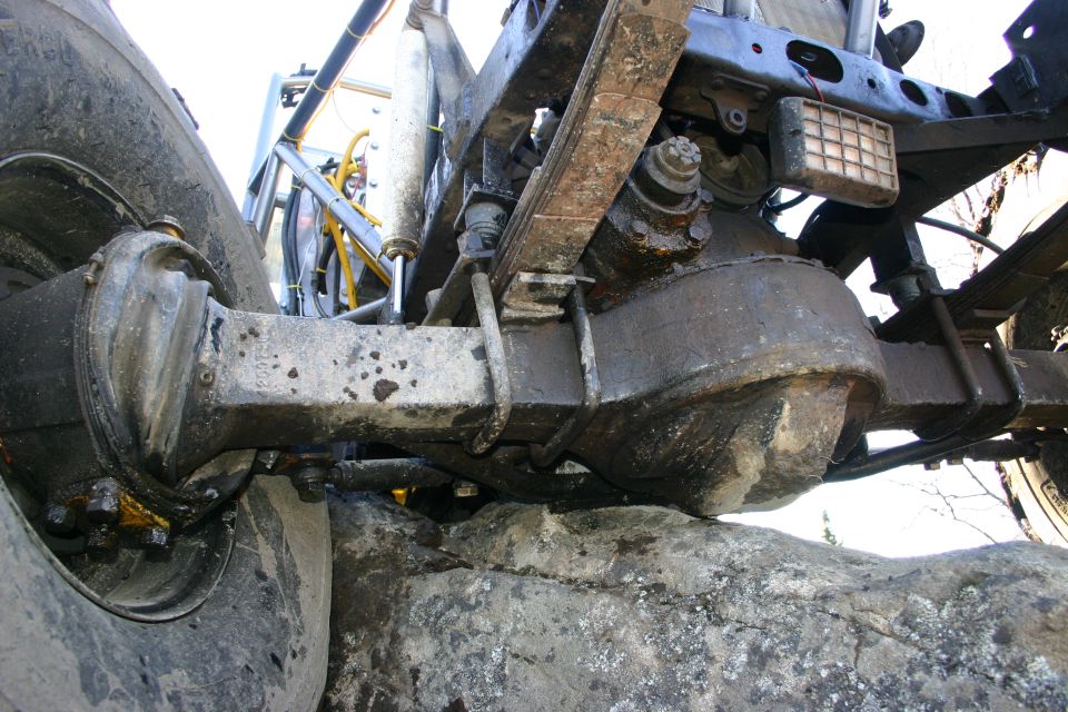 Off-road vehicle rear axle, leaf springs, and tire resting on rocks