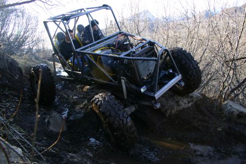 2003 Jeep TJ - Custom off-road buggy with occupants on a challenging, muddy terrain.