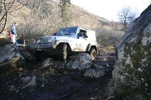 2003 Jeep TJ - A white 2003 Jeep TJ Rubicon navigates a rocky off-road trail.