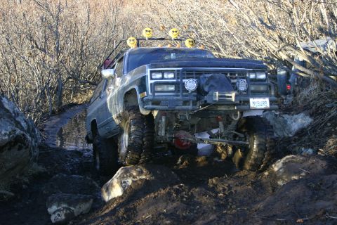 2003 Jeep TJ - This modified SUV appears to be from the 1980s, not a 2003 Jeep TJ, as it tackles a challenging off-road course.