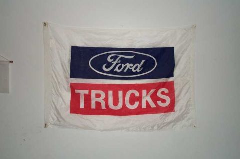 1988 Ford Bronco - Flag with Ford oval logo and 'TRUCKS' text hanging on a wall.