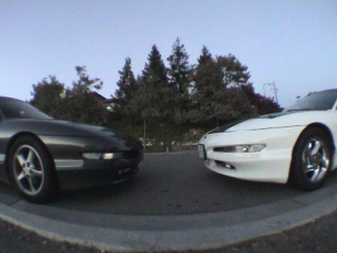 1997 Ford Probe - Two Ford Probes are parked facing each other on a street with trees in the background.