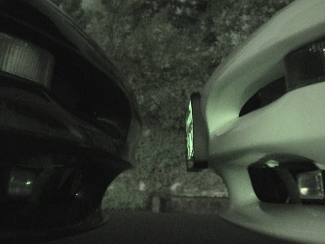Close-up of the front ends of two cars, one black and one white, parked closely together