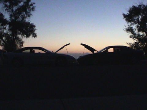 1997 Ford Probe - Two cars with their hoods open are silhouetted against the twilight sky.