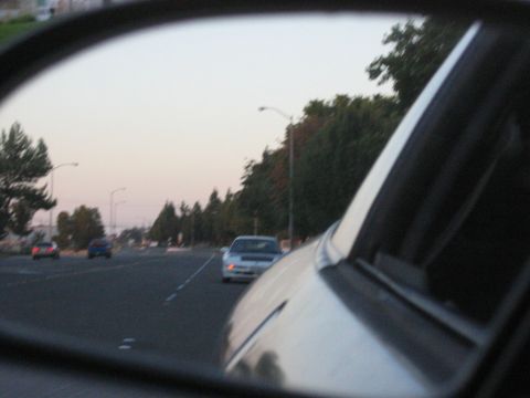 1997 Ford Probe - Traffic moves along a road as seen through a car's side mirror during twilight.