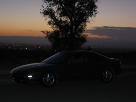 1997 Ford Probe - Coupe silhouetted against a twilight sky with distant city lights.