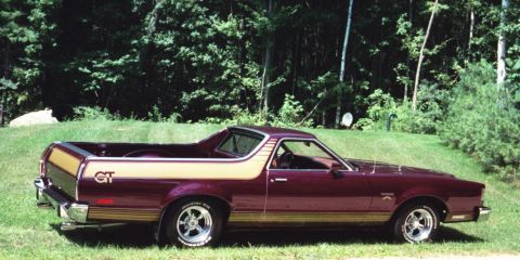 1972 Ford Ranchero - A maroon 1972 Ford Ranchero GT with a gold stripe is parked outdoors on a grassy area with trees in the background.