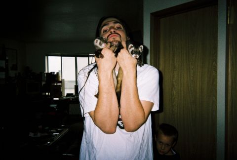 1990 Ford Bronco - A man poses with two ferrets in front of a window and a wooden door.