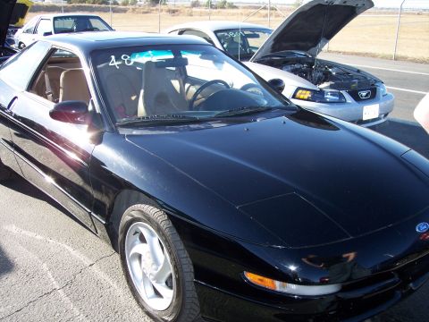 1993 Ford Probe - A black 1993 Ford Probe is parked next to other vehicles, one with its hood open.