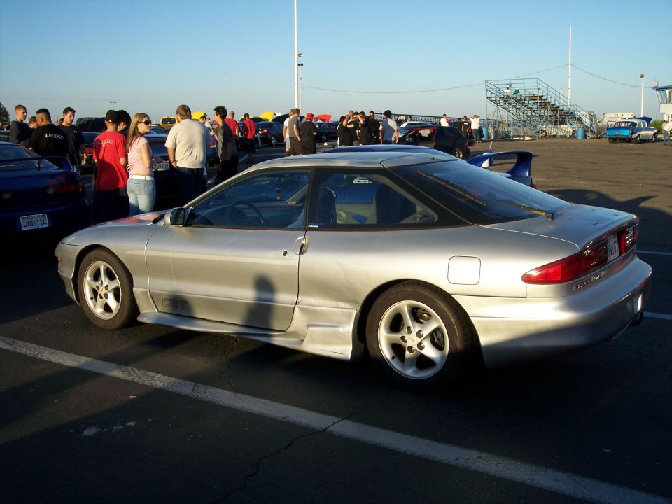 Silver 1993 Ford Probe parked outside with people around