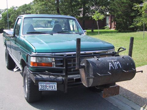 1993 Ford Bronco - This green pickup truck features a custom-built smoker grill attached to its front bumper, complete with the letters "ATM" painted on the s…