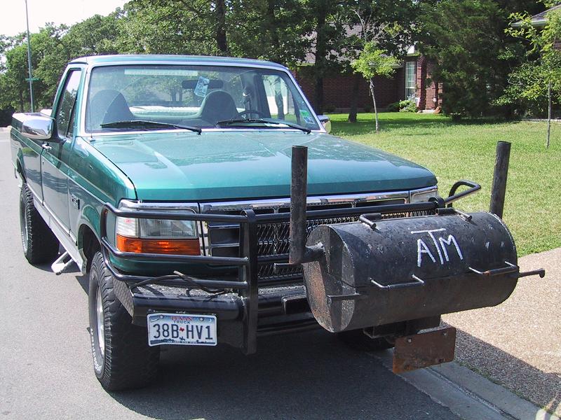 Green pickup truck with custom smoker grill on front bumper, license plate 38B-HV1