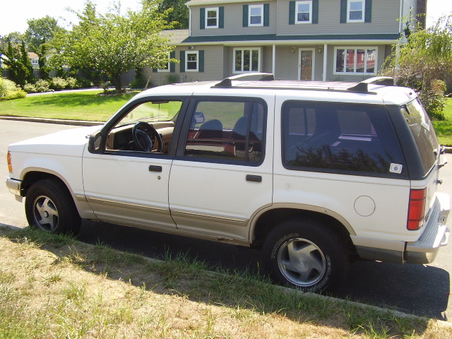White 1991 Ford Explorer parked on a grassy curb, side view