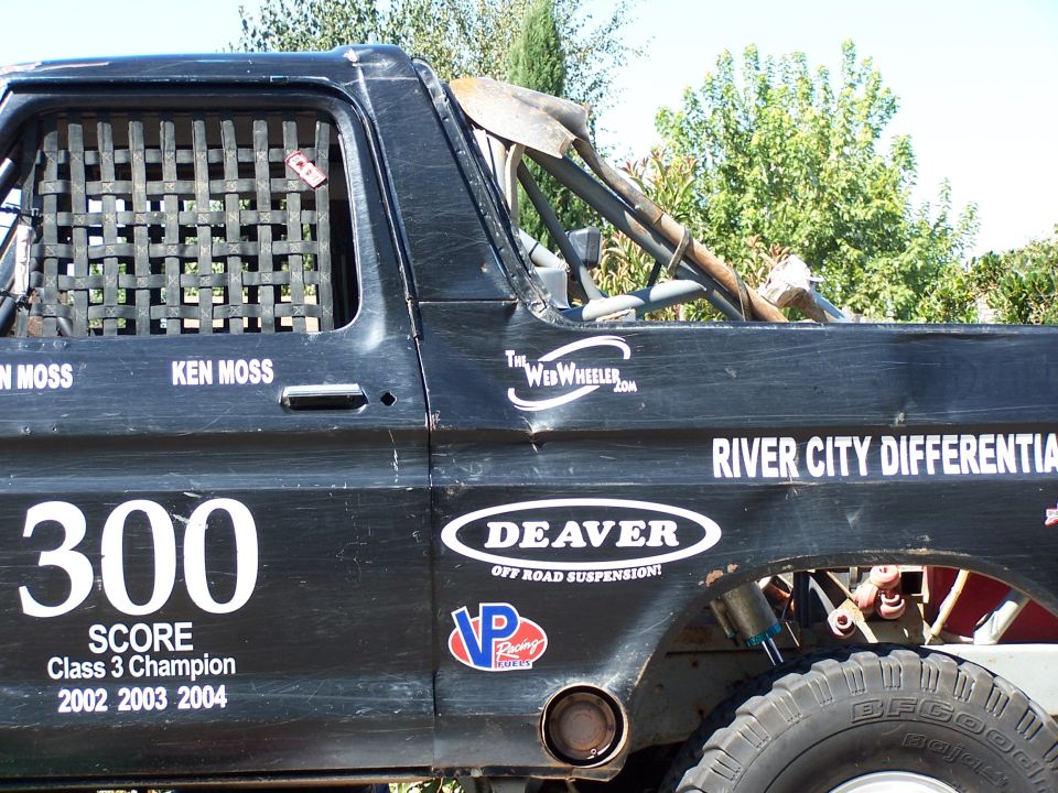 Side view of a black off-road race truck with number 300 and various sponsor decals