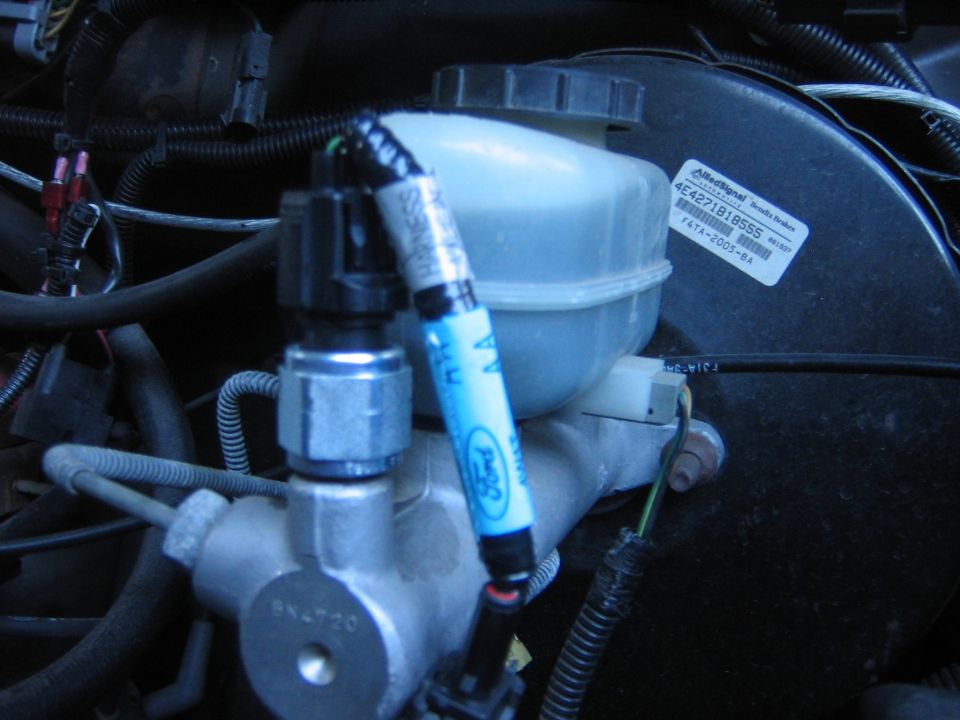 Engine bay brake master cylinder and reservoir with Ford labels, marked with a blue paint pen
