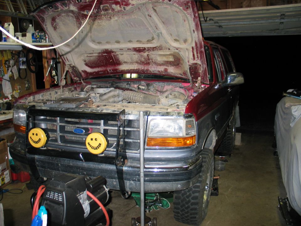 1995 Ford Bronco front view, hood open, in garage with yellow fog lights