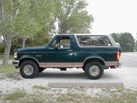 1994 Ford Bronco - Side profile of a green 1994 Ford Bronco, tan lower body trim and a removable hardtop.