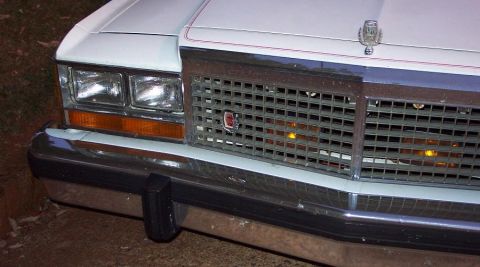 1985 Ford Crown Victoria LTD - Close-up of the front grille and headlights of a white Ford Crown Victoria, likely from the early 1980s.