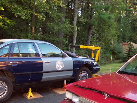 2001 Ford Crown Victoria - A Ford Crown Victoria, painted in two distinct colors, is elevated on jack stands next to another vehicle.