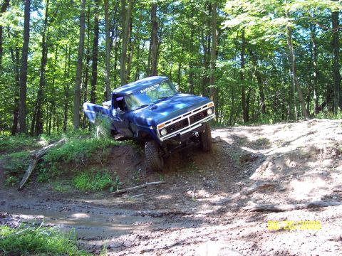 1977 Ford F-150 - A blue 1977 Ford F-150 navigates a muddy, wooded trail.