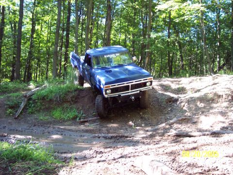 1977 Ford F-150 - This blue 1977 Ford F-150 navigates a challenging off-road course through a wooded area.