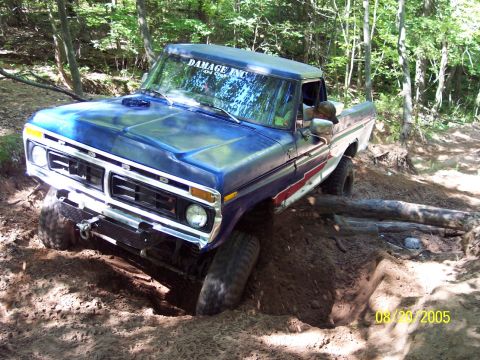 1977 Ford F-150 - A blue 1977 Ford F-150 navigates a muddy obstacle on an off-road trail.