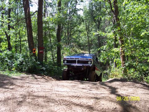 1977 Ford F-150 - This 1977 Ford F-150 is captured navigating a wooded trail with a dirt path.