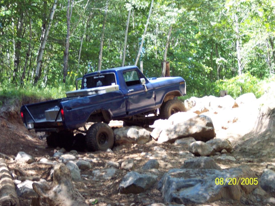 blue 1977 Ford F-150 climbing over rocks on a trail