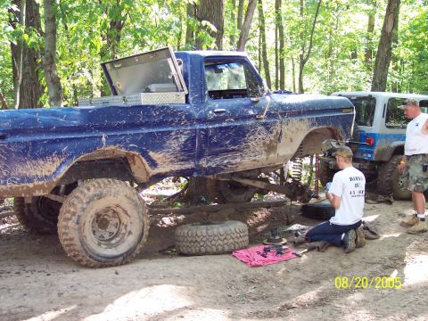 1977 Ford F-150 - A muddy blue 1977 Ford F-150 pickup truck is undergoing maintenance outdoors, with another vehicle visible in the background.