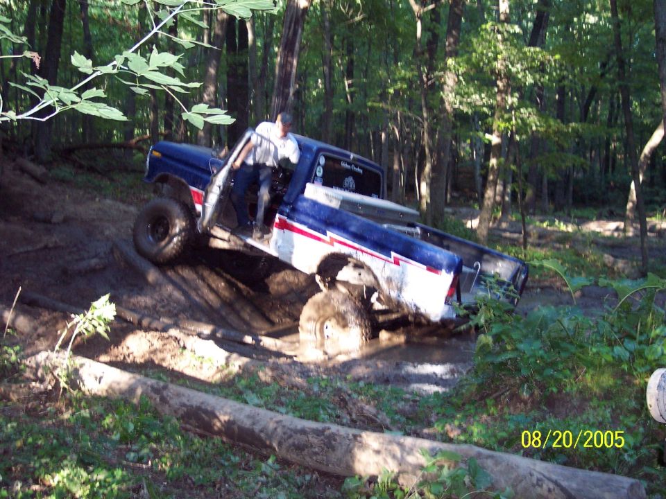 1977 Ford F-150 navigating a muddy off-road trail with the front passenger door open