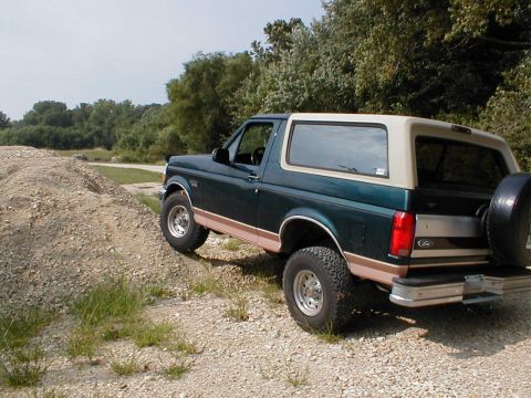 1994 Ford Bronco - Green 1994 Ford Bronco with tan top on a gravelly dirt road.