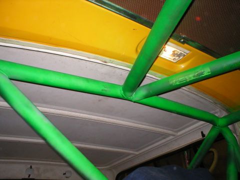 1978 Ford Bronco - The interior of a vehicle shows a custom green roll cage installed under the headliner.