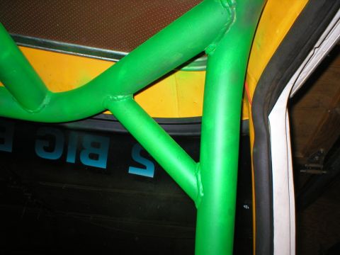 1978 Ford Bronco - A close-up view of a bright green roll cage installed inside a vehicle, with some blue lettering visible on the interior paneling interior…