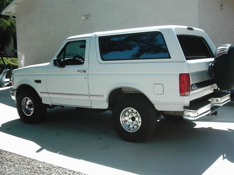 1978 Ford Bronco - This white Ford Bronco is parked on a concrete driveway next to a building.