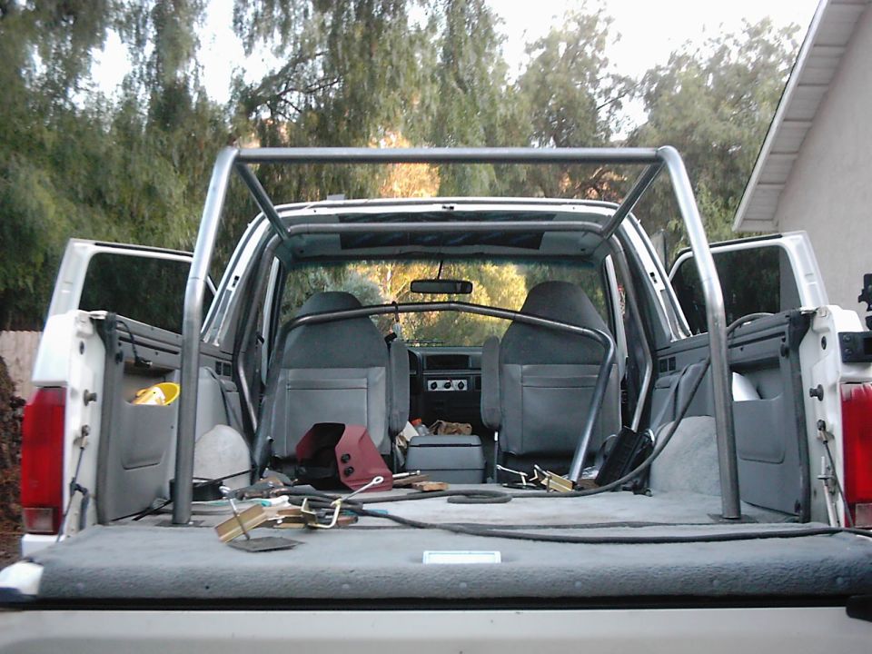 Interior of white SUV with roll cage, showing seats and cargo area