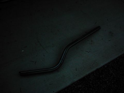 1978 Ford Bronco - A bent metal rod lies on a dark, textured surface.