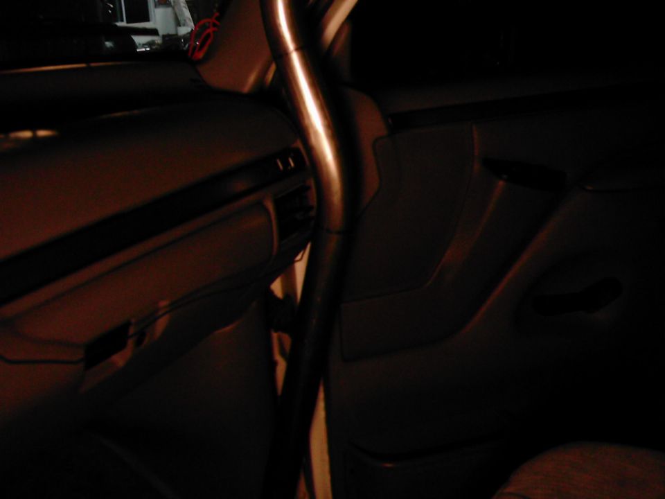 Interior view of a vehicle with a roll cage and dark upholstery