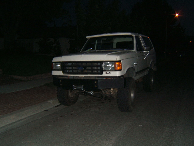 1988 Ford Bronco with aftermarket bumper and winch, parked on a street at night