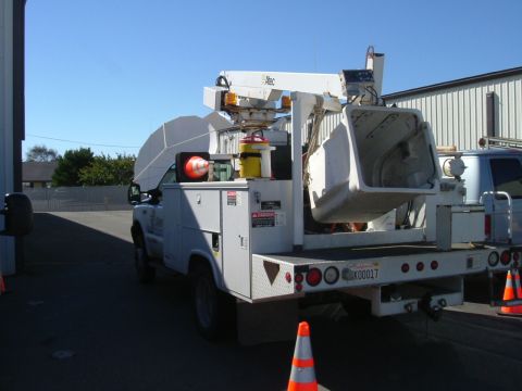 1993 Ford Bronco - A white utility truck equipped with a bucket lift is seen from the rear, with another vehicle partially visible to the right.