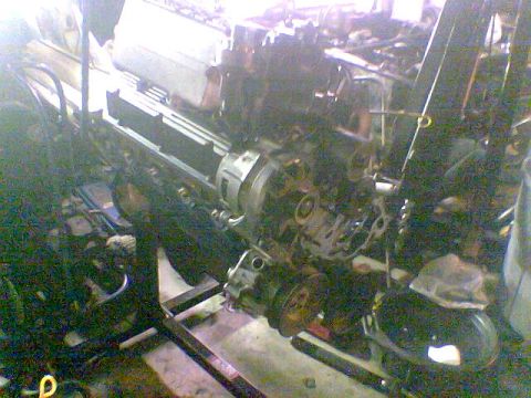1988 Ford Bronco - Engine assembly on a stand, with hoses and mechanical parts visible.
