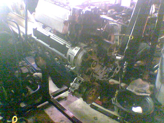 Engine out of the vehicle on a stand, alternator and accessory brackets visible