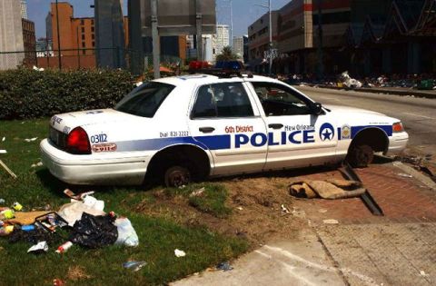 1972 Ford Ranchero - A New Orleans police car sits abandoned on the side of the road, missing its wheels and surrounded by debris.