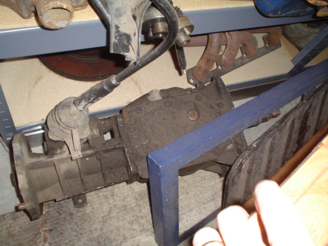 Greasy steering gearbox in a vise area of a garage with a hand and exhaust manifold nearby